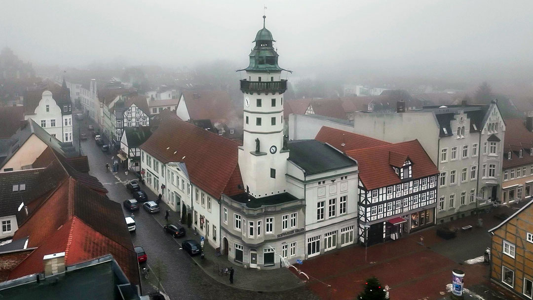 Luftansicht der historischen Altstadt von Salzwedel mit dem markanten Rathausturm im Nebel.